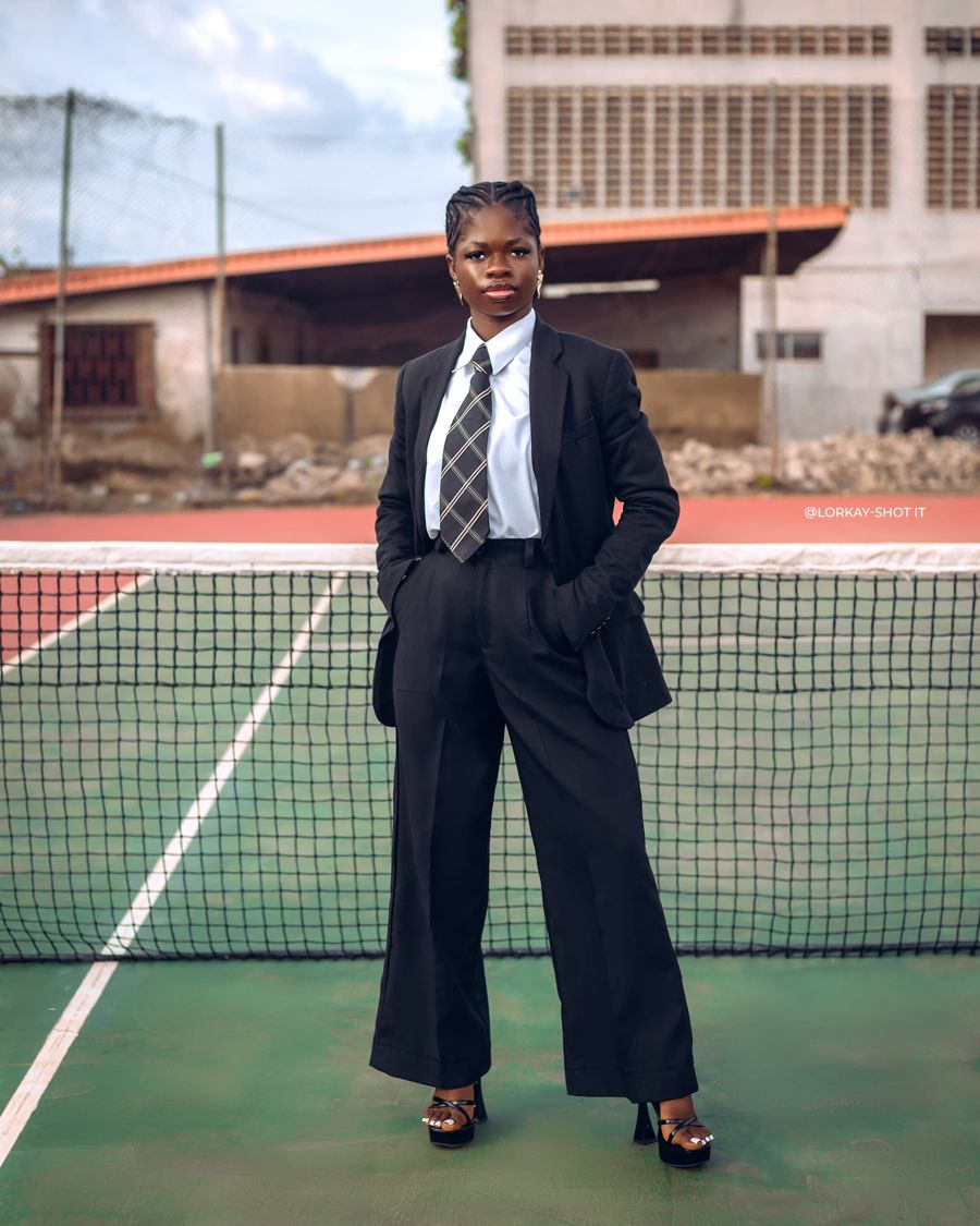 Olubunmi Elizabeth standing on a tennis court in a black suit